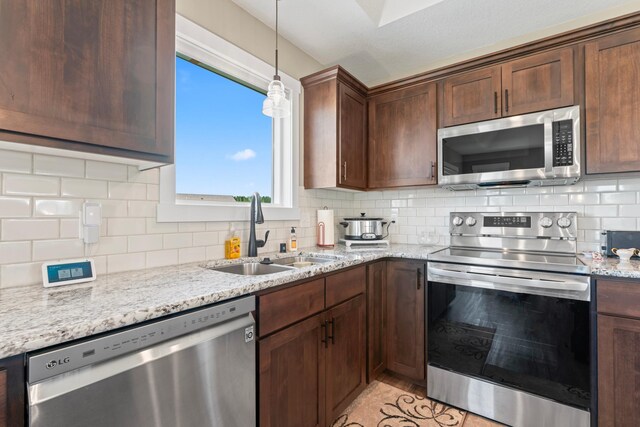 409 10th St NW, Dodge Center, MN 55927 - kitchen featuring stainless steel appliances, a sink, backsplash, and light stone counters