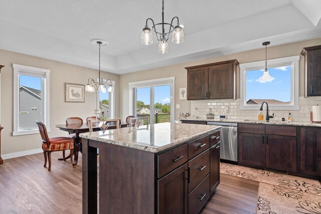 409 10th St NW, Dodge Center, MN 55927 - kitchen with stainless steel dishwasher, a tray ceiling, a chandelier, wood finished floors, and a sink