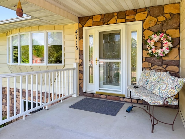 view of exterior entry featuring a porch and stone siding
