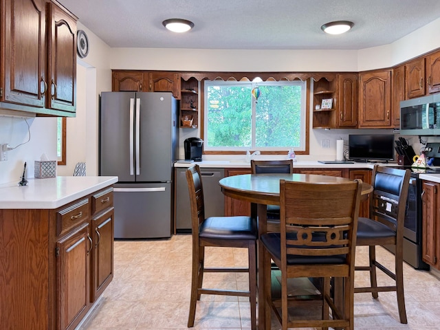 kitchen with appliances with stainless steel finishes, open shelves, light countertops, and a textured ceiling