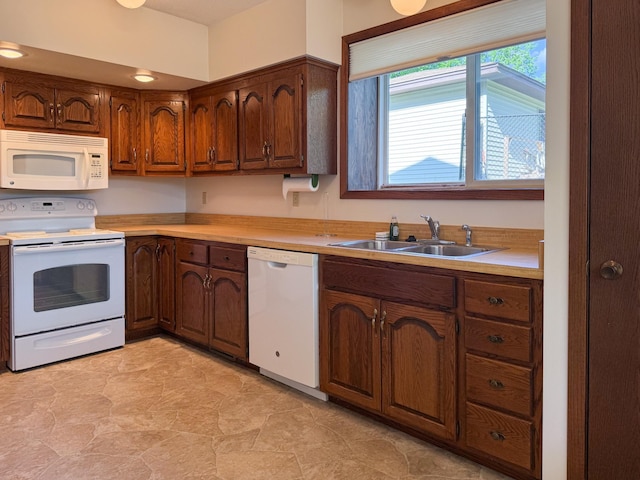 kitchen featuring white appliances, a sink, and light countertops