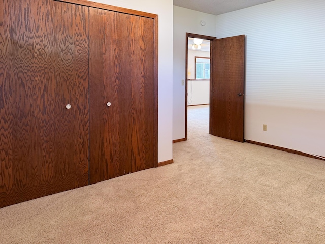 unfurnished bedroom featuring carpet, baseboards, and a closet