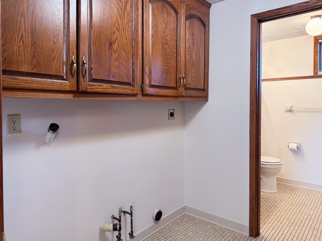 laundry area with electric dryer hookup, cabinet space, baseboards, and tile patterned flooring