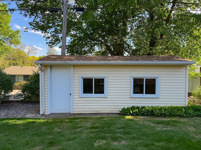 back of property featuring a yard and a shingled roof
