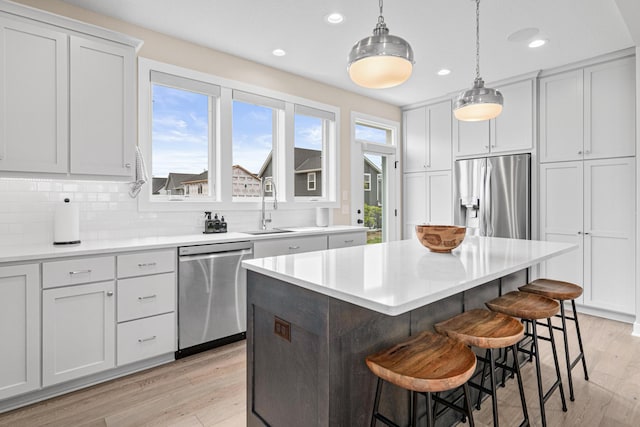 5068 Airlake Draw, Woodbury, MN 55129 - kitchen with stainless steel appliances, light wood finished floors, recessed lighting, a kitchen island, and a breakfast bar area