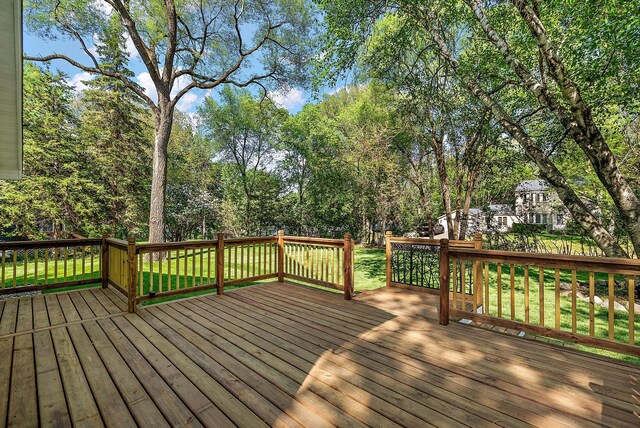 wooden terrace with a yard and view of wooded area