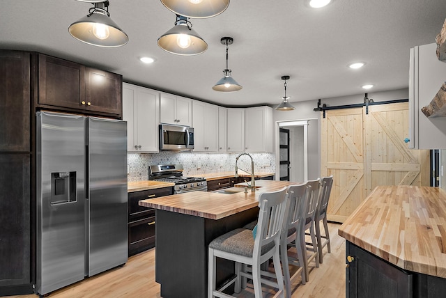 kitchen with wooden counters, stainless steel appliances, a sink, light wood-style flooring, and recessed lighting