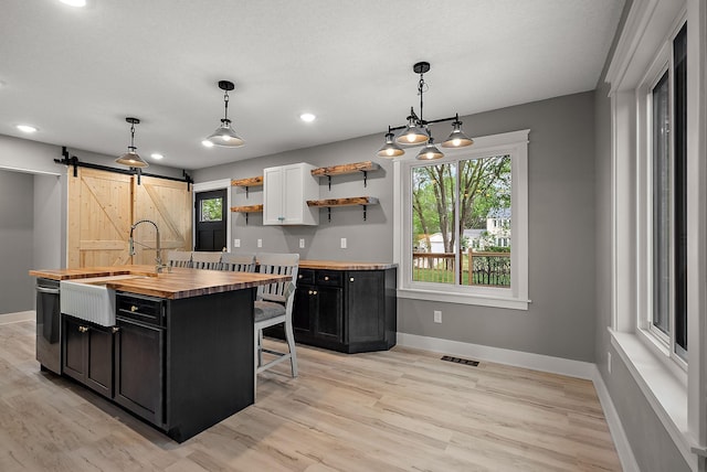 kitchen with wood counters, dark cabinets, a sink, baseboards, and recessed lighting