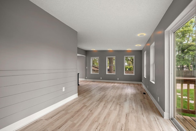 spare room featuring healthy amount of natural light, light wood-type flooring, and baseboards