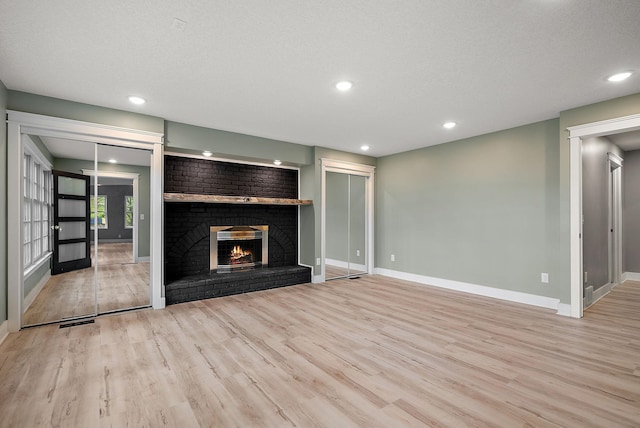 unfurnished living room with wood finished floors, baseboards, a fireplace, and recessed lighting