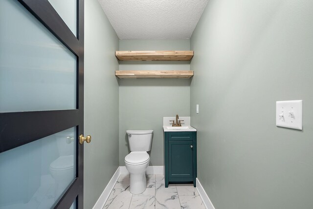 half bath featuring toilet, marble look tiles, vanity, baseboards, and a textured ceiling