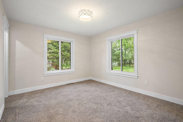 carpeted empty room featuring baseboards and a textured ceiling