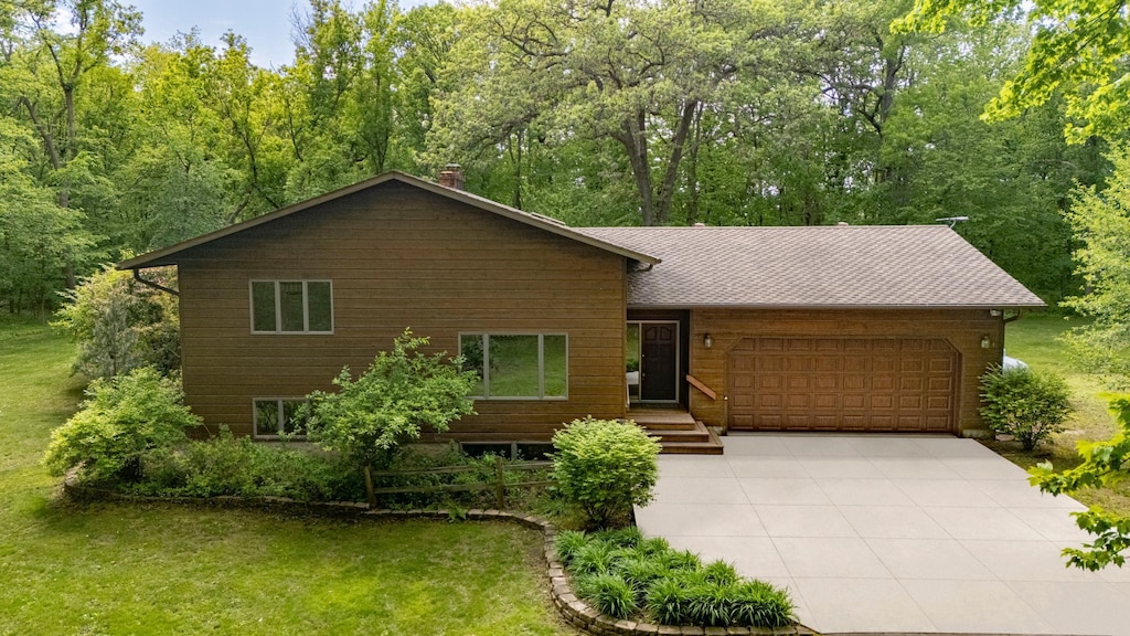 N8545 1205th St, Clifton Twp, WI 54022 - chalet / cabin with an attached garage, concrete driveway, a chimney, and a front lawn