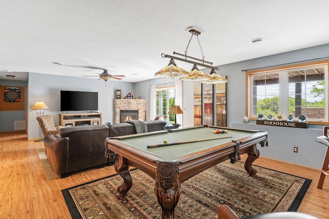33401 Lakes Trl, Chisago Lake Twp, MN 55045 - rec room with a stone fireplace, a textured ceiling, a ceiling fan, light wood-type flooring, and billiards