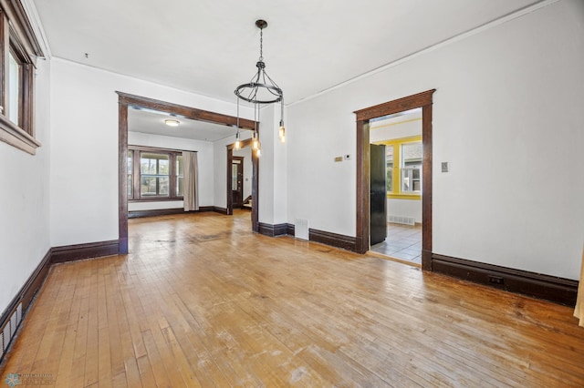 unfurnished room with light wood-style floors, baseboards, and crown molding