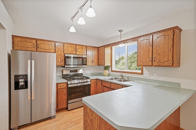 2191 Grimm Rd, Chaska, MN 55318 - kitchen with stainless steel appliances, a sink, a peninsula, brown cabinetry, and lofted ceiling