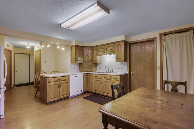 607 Wilson St, Downing, WI 54734 - kitchen featuring white appliances, a sink, light wood-style floors, a peninsula, and a textured ceiling