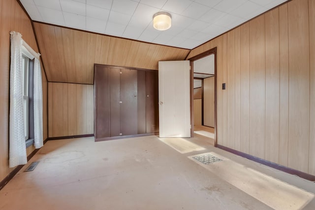 607 Wilson St, Downing, WI 54734 - unfurnished bedroom featuring concrete floors, wooden walls, a closet, and baseboards
