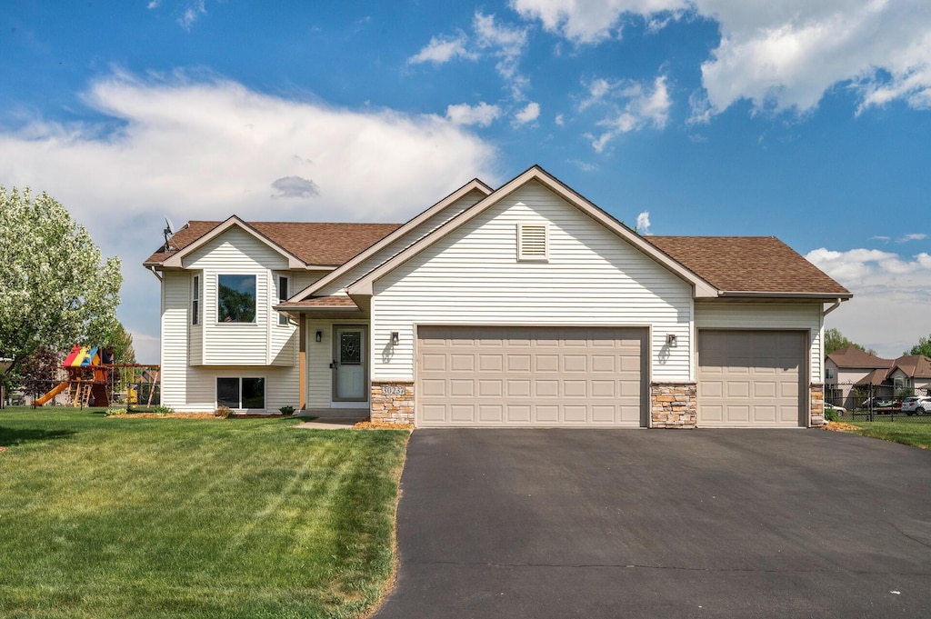 30237 Fox Run Rd, Stacy, MN 55079 - split level home with asphalt driveway, a garage, a front lawn, and stone siding