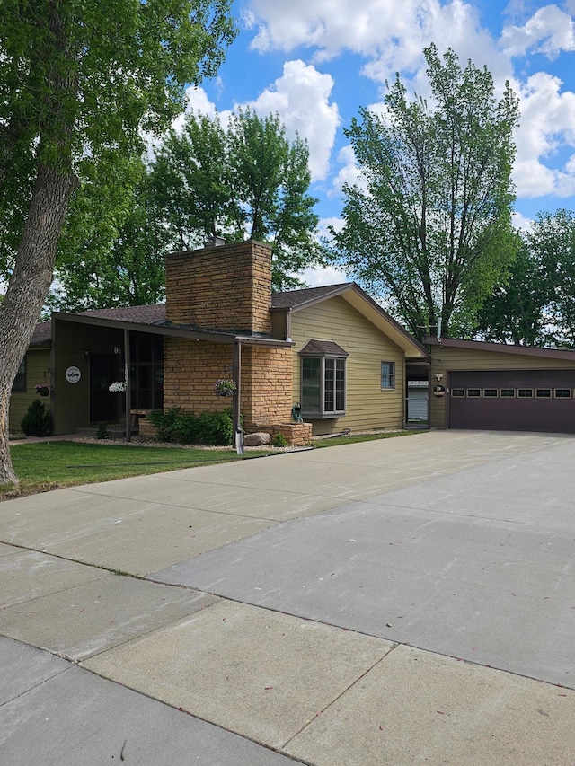 1005 8th Ave SW, Pipestone, MN 56164 - view of front of property featuring concrete driveway, a garage, and a chimney