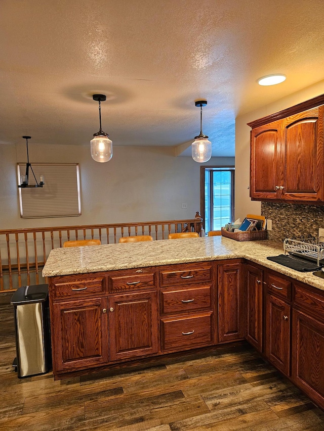 1005 8th Ave SW, Pipestone, MN 56164 - kitchen with decorative light fixtures, a textured ceiling, decorative backsplash, dark wood finished floors, and a peninsula