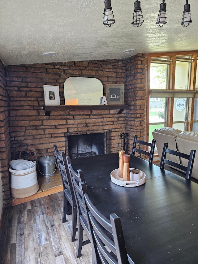 1005 8th Ave SW, Pipestone, MN 56164 - dining room featuring a brick fireplace, a textured ceiling, and wood finished floors