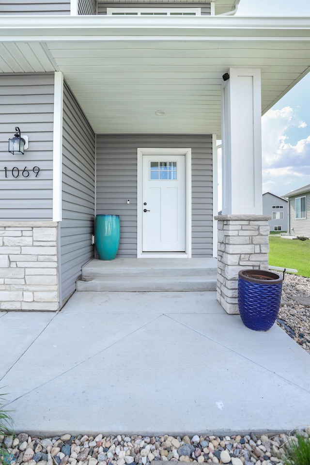 doorway to property featuring covered porch and stone siding