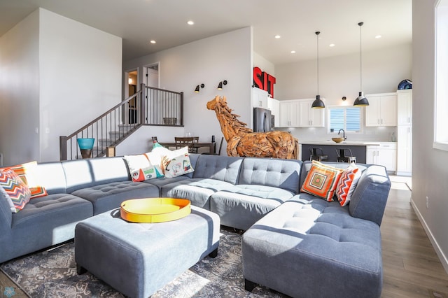 living room with dark wood finished floors, stairs, recessed lighting, a towering ceiling, and baseboards