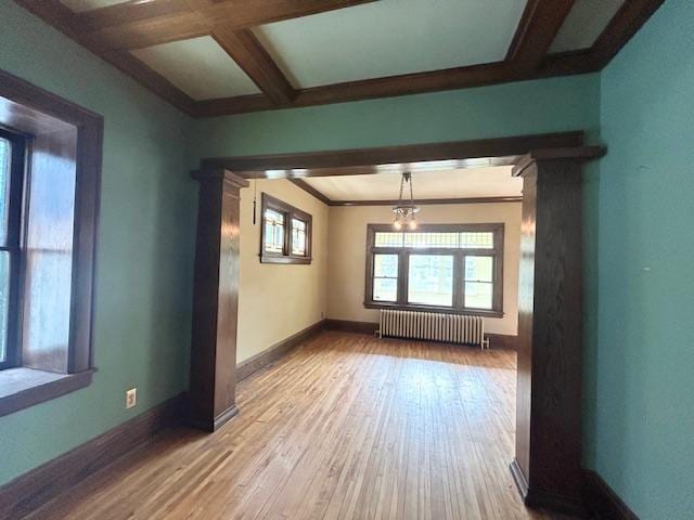 spare room featuring radiator heating unit, hardwood / wood-style floors, baseboards, beam ceiling, and coffered ceiling