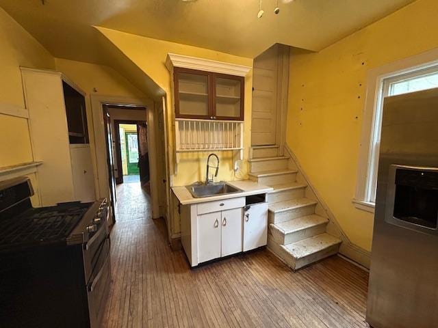 kitchen with stainless steel gas stove, a sink, hardwood / wood-style flooring, and plenty of natural light