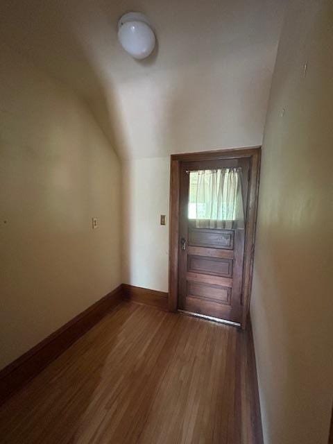 entryway featuring wood finished floors, lofted ceiling, and baseboards