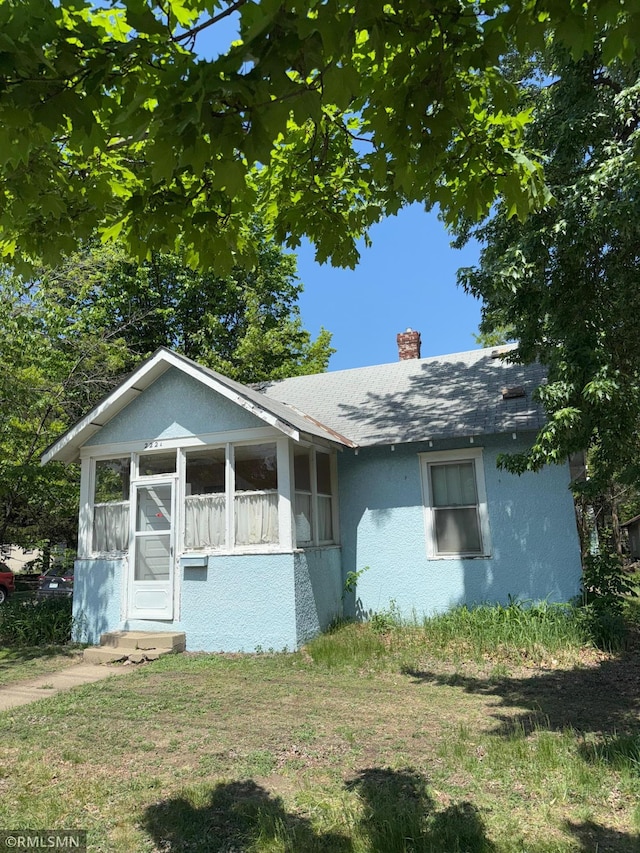 2224 42nd St, Minneapolis, MN 55407 - view of front of house with a chimney, a sunroom, stucco siding, and a shingled roof