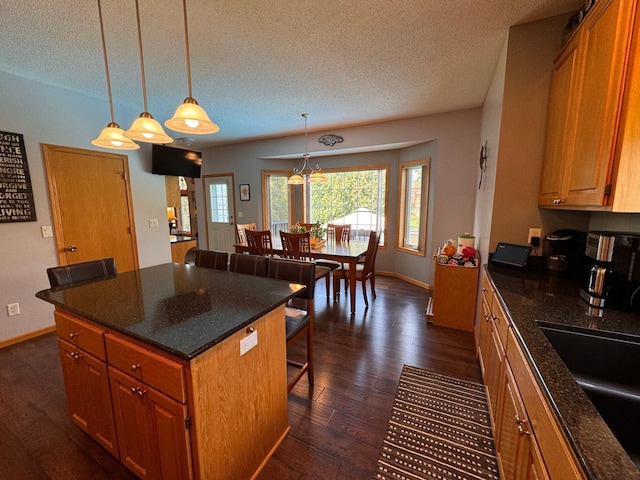 6158 Forest Boulevard Trl, Wyoming, MN 55092 - kitchen with dark wood-style flooring, a breakfast bar, a textured ceiling, a sink, and brown cabinetry