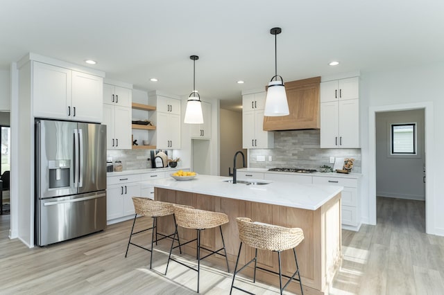 kitchen with stainless steel fridge, a sink, open shelves, tasteful backsplash, and light wood finished floors