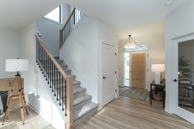 entrance foyer featuring light wood-style floors, stairs, and baseboards