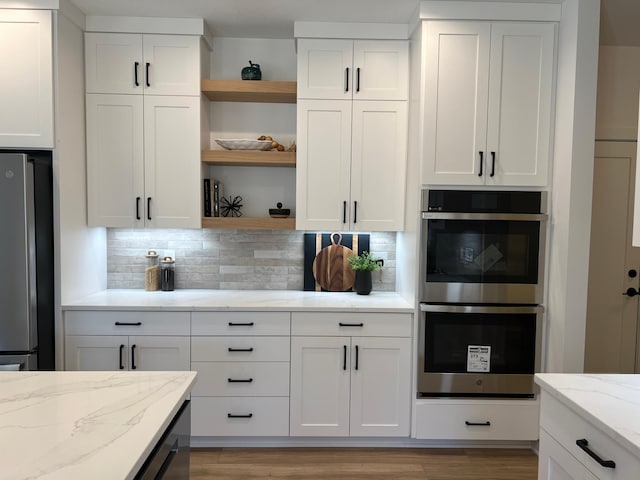 kitchen with appliances with stainless steel finishes, open shelves, white cabinetry, and tasteful backsplash
