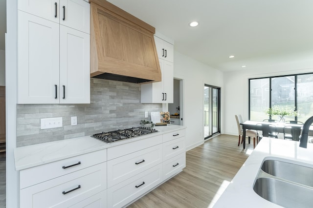 kitchen with stainless steel gas stovetop, premium range hood, recessed lighting, backsplash, and a sink