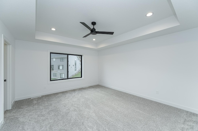 unfurnished room featuring a raised ceiling, ceiling fan, carpet, baseboards, and recessed lighting