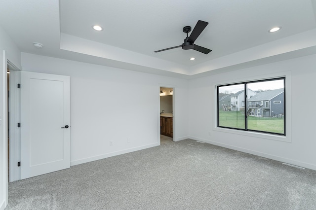 unfurnished bedroom with a raised ceiling, carpet flooring, baseboards, recessed lighting, and ensuite bathroom