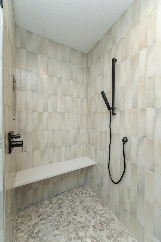 bathroom featuring stone finish flooring and a tile shower
