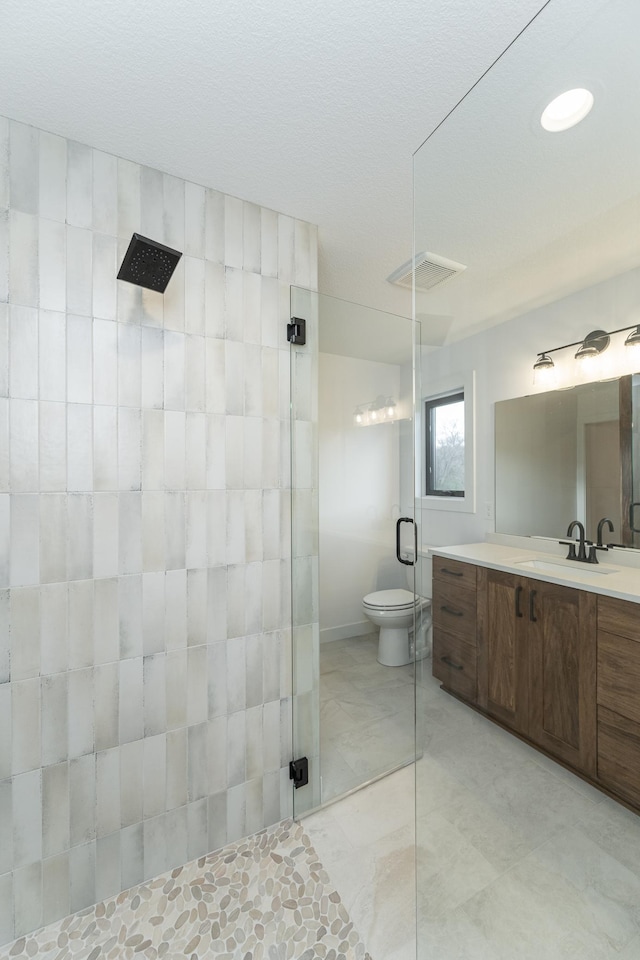 bathroom with tiled shower, vanity, toilet, and marble finish floors