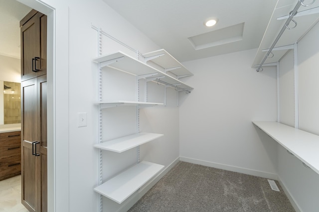 spacious closet with light colored carpet and attic access