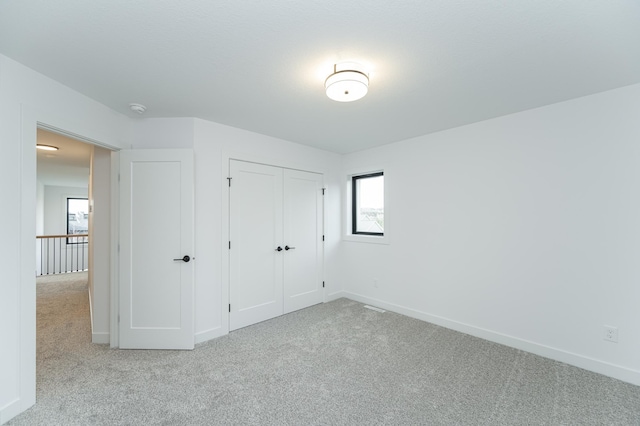 unfurnished bedroom featuring carpet, baseboards, and a closet