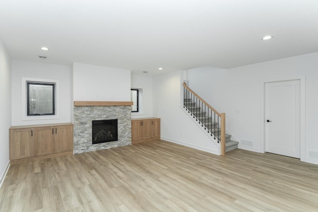 unfurnished living room with light wood-style floors, stairway, recessed lighting, a fireplace, and baseboards