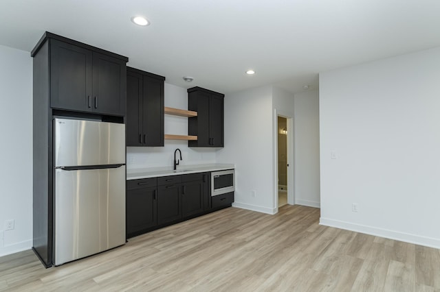 kitchen featuring appliances with stainless steel finishes, open shelves, a sink, light wood-style floors, and recessed lighting