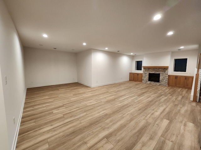 unfurnished living room with light wood finished floors, recessed lighting, a fireplace, and baseboards