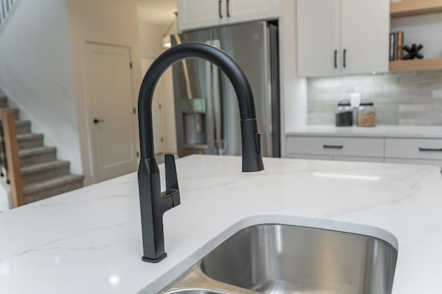 kitchen view of a sink, open shelves, white cabinets, and decorative backsplash