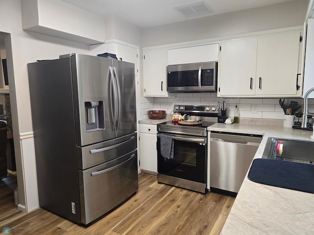 2105 7th St S, Moorhead, MN 56560 - kitchen featuring stainless steel appliances, light countertops, wood finished floors, white cabinetry, and tasteful backsplash