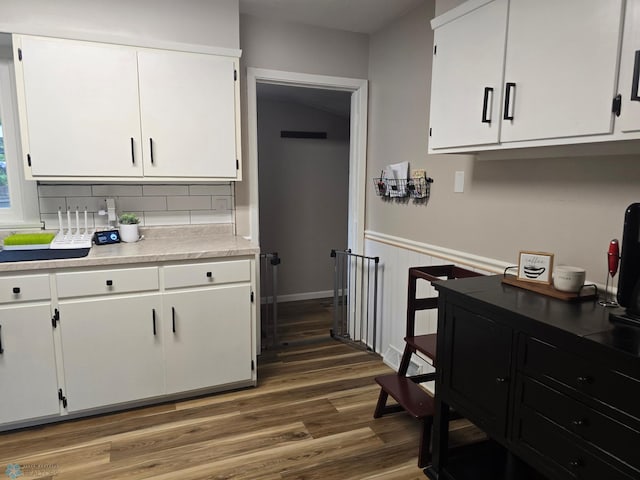 2105 7th St S, Moorhead, MN 56560 - kitchen with white cabinets, dark wood-style floors, light countertops, backsplash, and a wainscoted wall