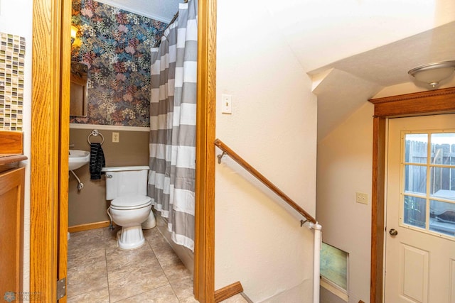 bathroom with toilet, vaulted ceiling, curtained shower, and baseboards